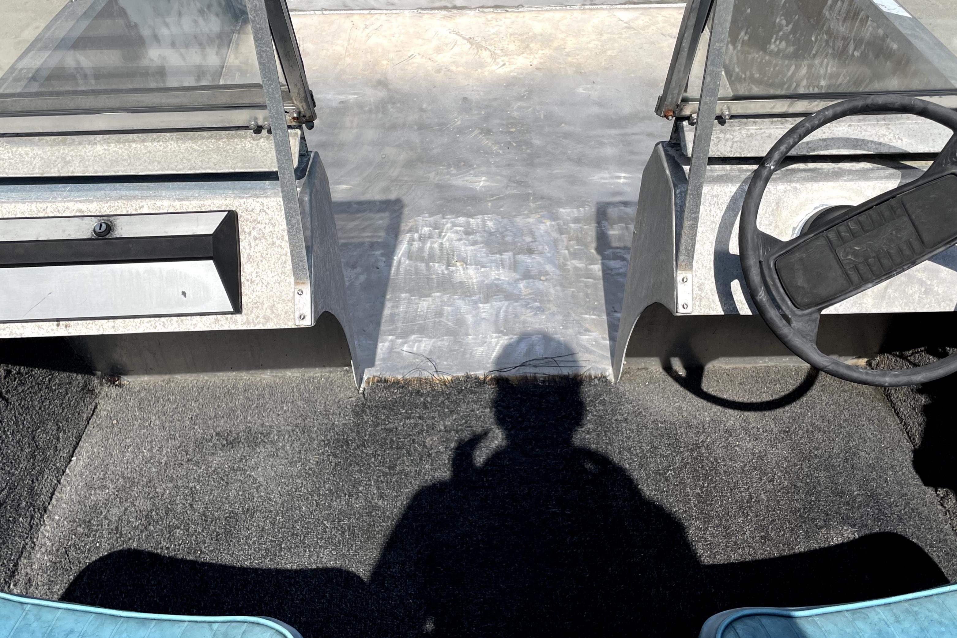 Interior of a 1994 Custom Aluminum 15 boat with steering wheel and shadow.