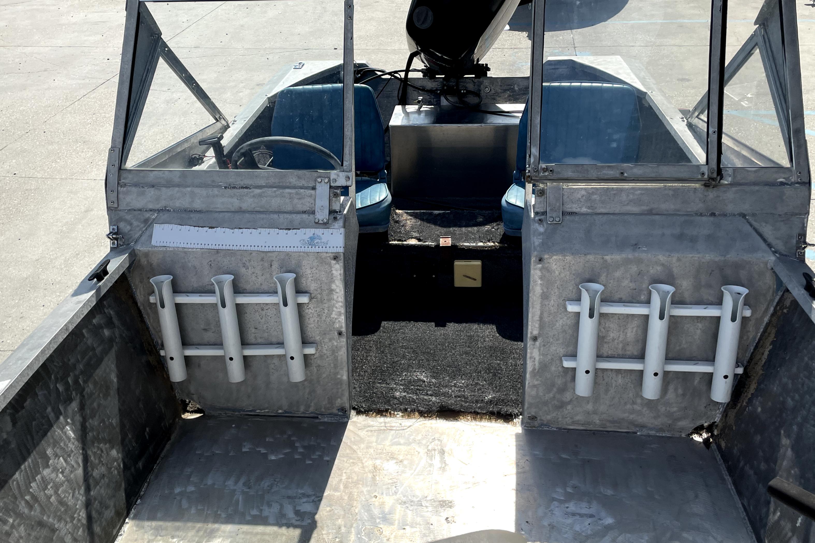 Interior of a 1994 Custom Aluminum 15 boat with rod holders and blue seats.