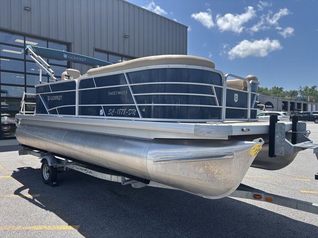 2021 Godfrey SW 2086 C pontoon boat on trailer, parked outside a building.