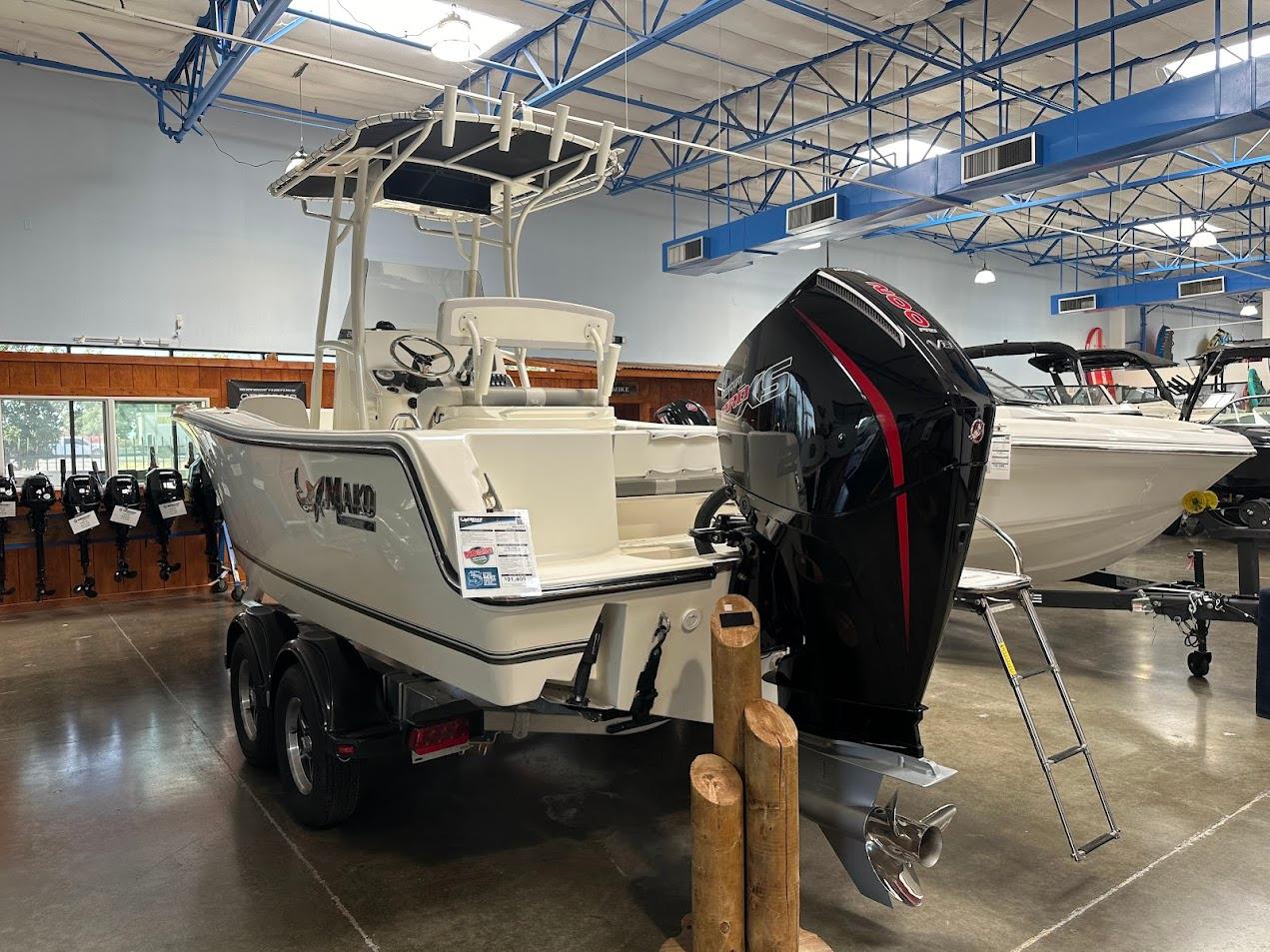 2025 Mako 214 CC boat displayed indoors with powerful outboard motor.