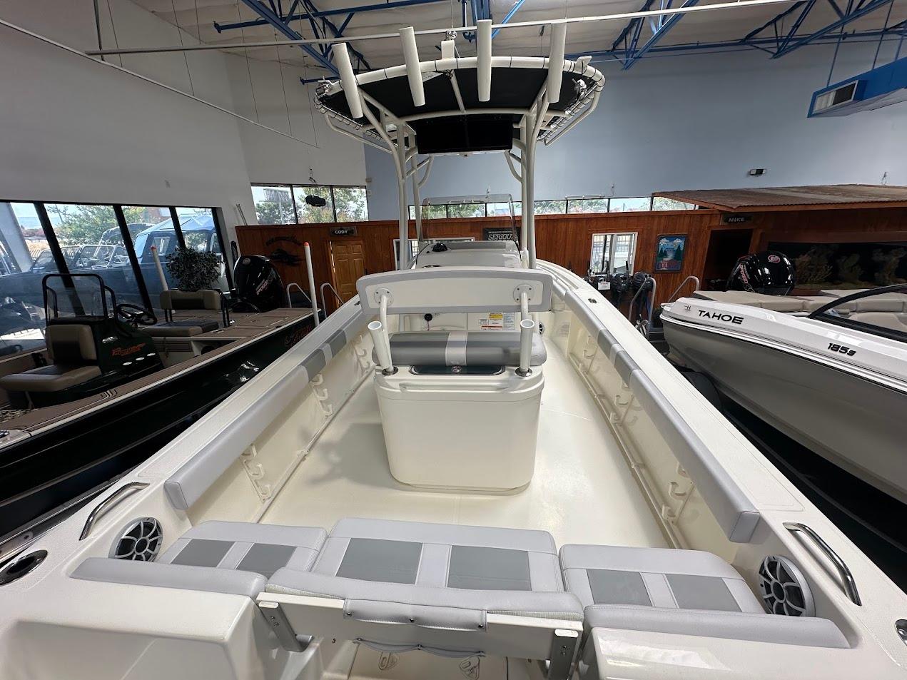 2025 Mako 214 CC boat interior with seating and storage, displayed in a showroom.