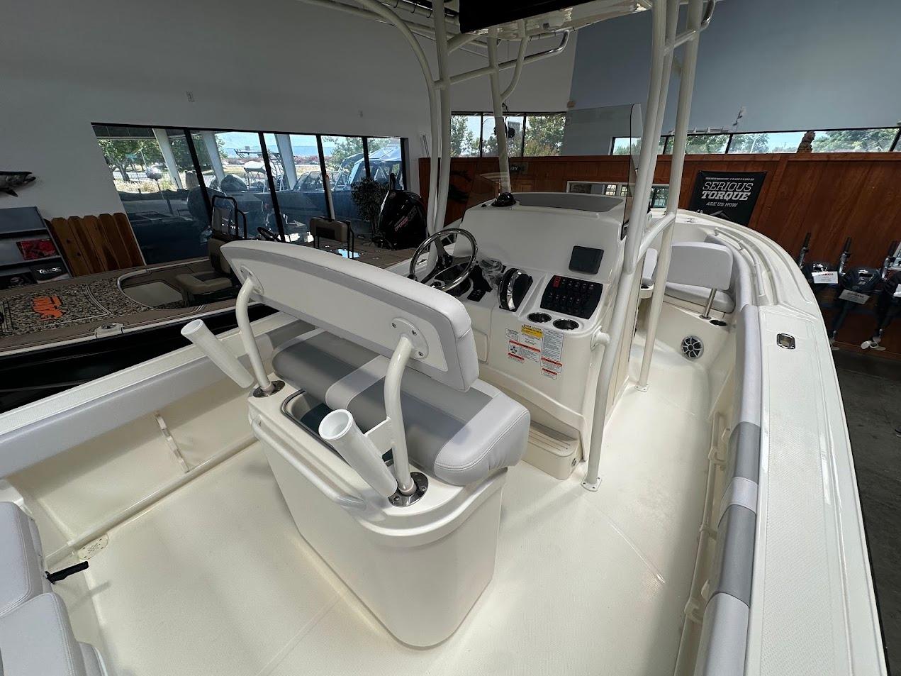 2025 Mako 214 CC boat interior with helm, seating, and controls in showroom.