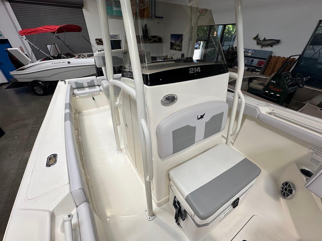 2025 Mako 214 CC boat interior with seating and storage, displayed in a showroom.