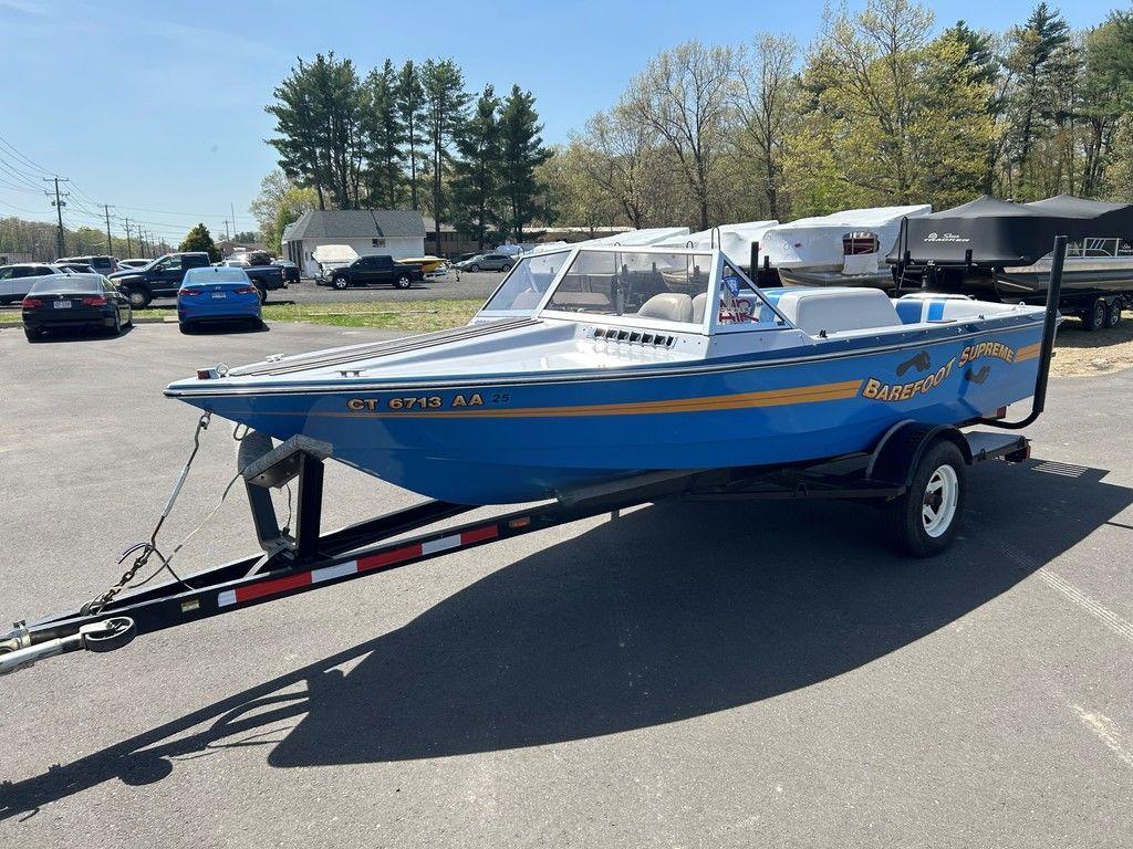 1980 Ski Supreme boat on trailer in parking lot, blue with yellow accents.