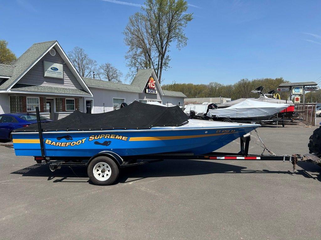 1980 Ski Supreme boat on trailer, blue with yellow stripe, parked outdoors.