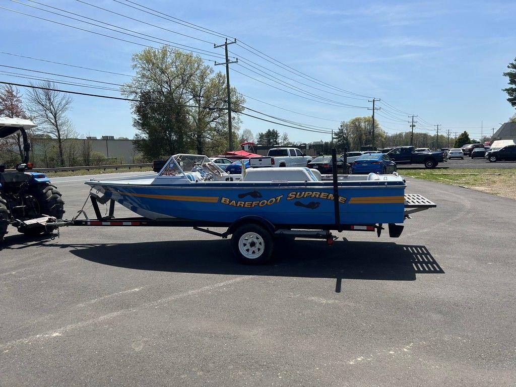 1980 Ski Supreme boat on trailer, blue and yellow design, parked outdoors.