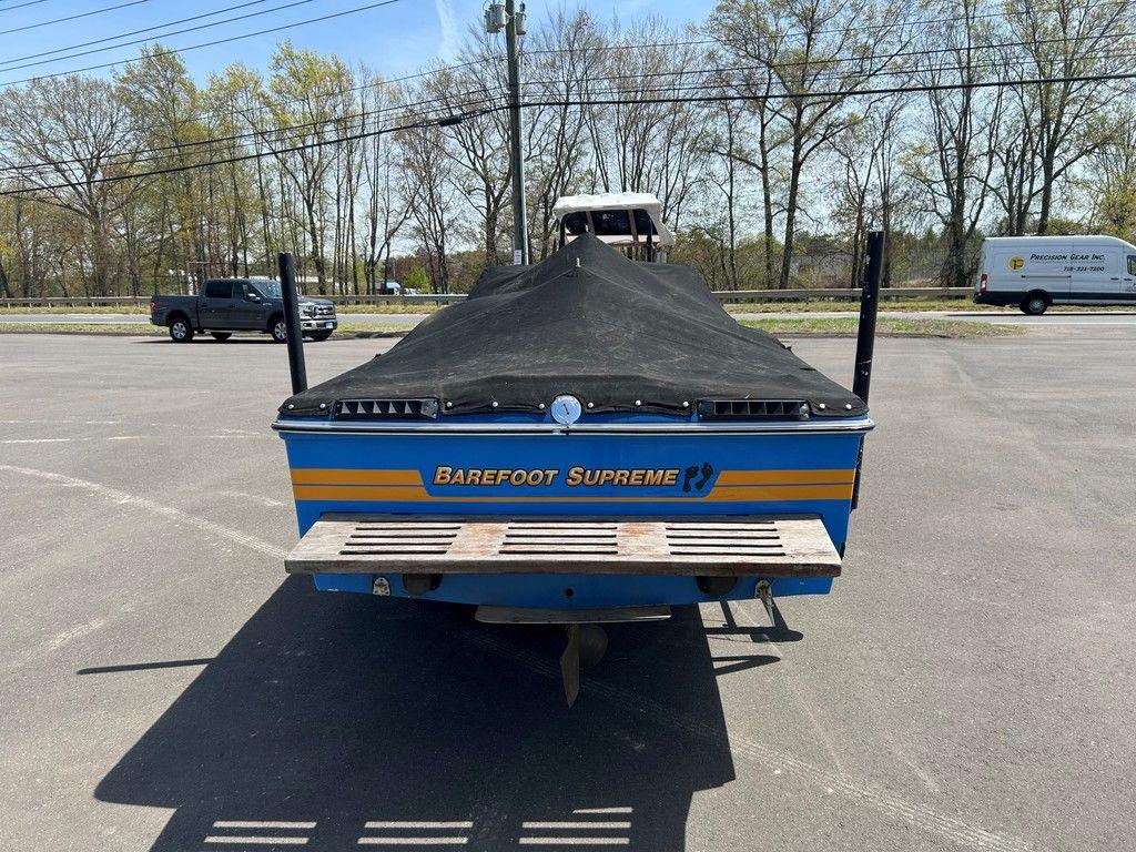 1980 Ski Supreme boat with cover, parked in a lot, rear view.