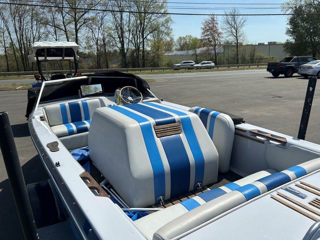 1980 Ski Supreme boat with blue and white striped interior, parked outdoors.