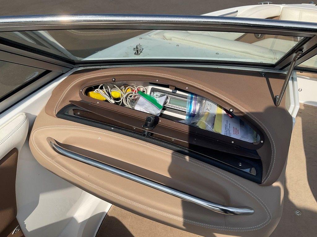 Storage compartment in a 2013 Cobalt 210 boat, containing various items and accessories.