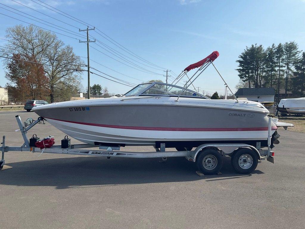 2013 Cobalt 210 boat on trailer, parked outdoors, with trees and power lines in background.