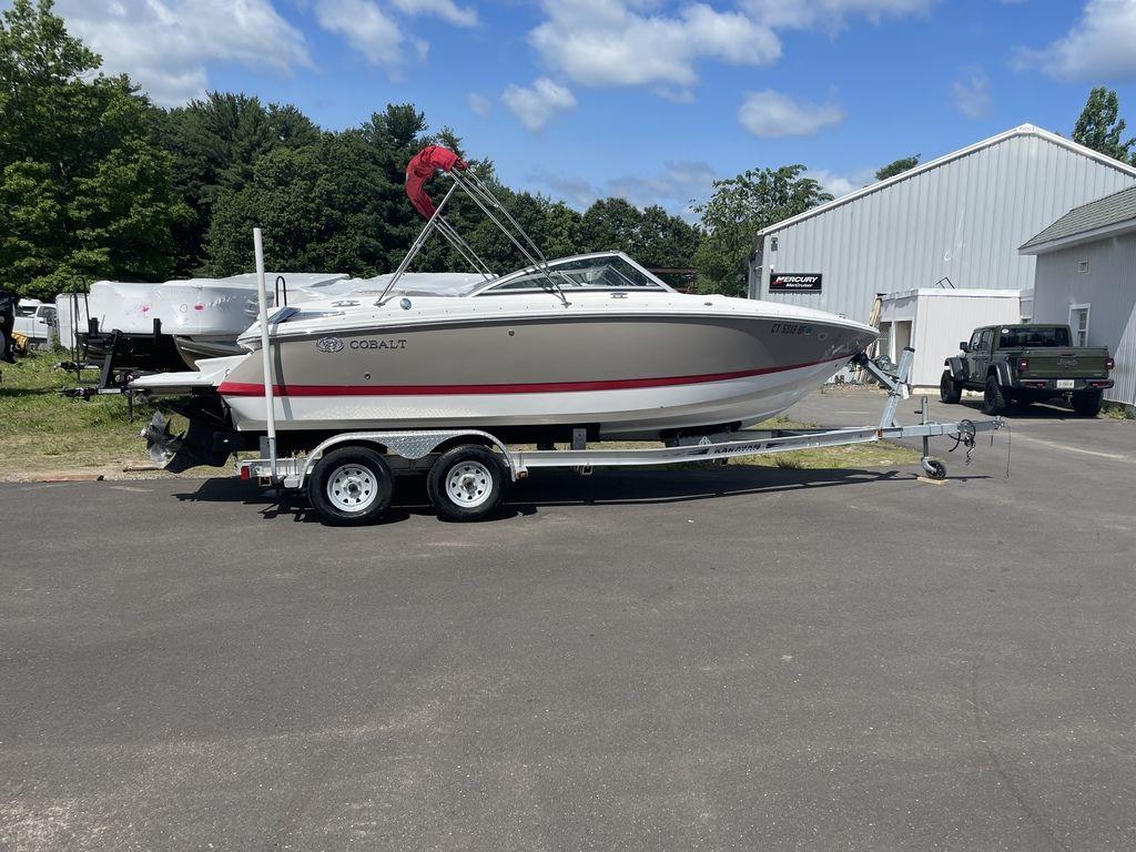 2013 Cobalt 210 boat on trailer, parked outdoors near a white building.