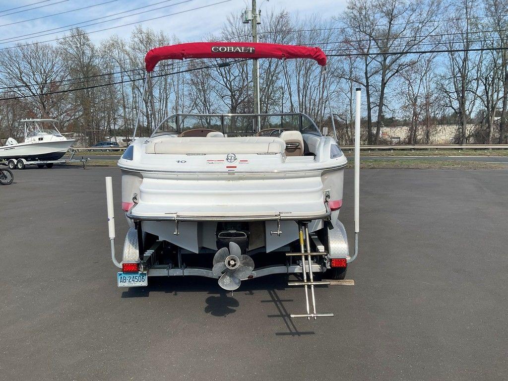 2013 Cobalt 210 boat with red canopy, parked on a trailer, rear view.