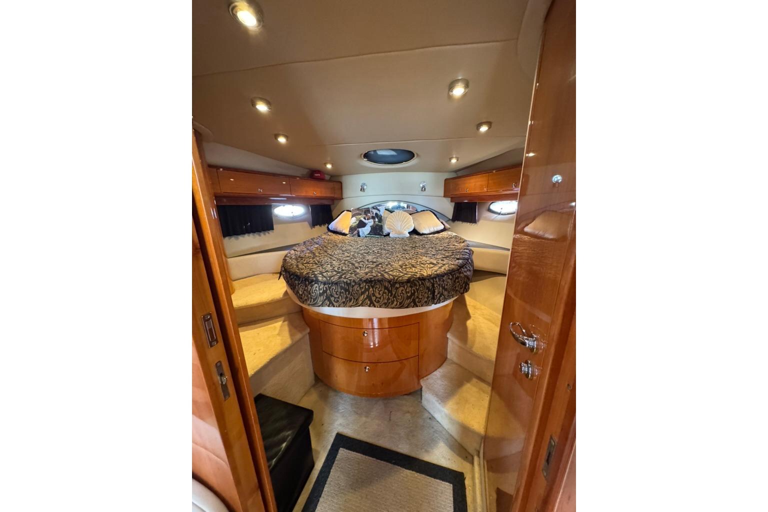 Luxurious 2006 Regal Commodore 4460 yacht cabin with elegant wood finishes and cozy bedding.