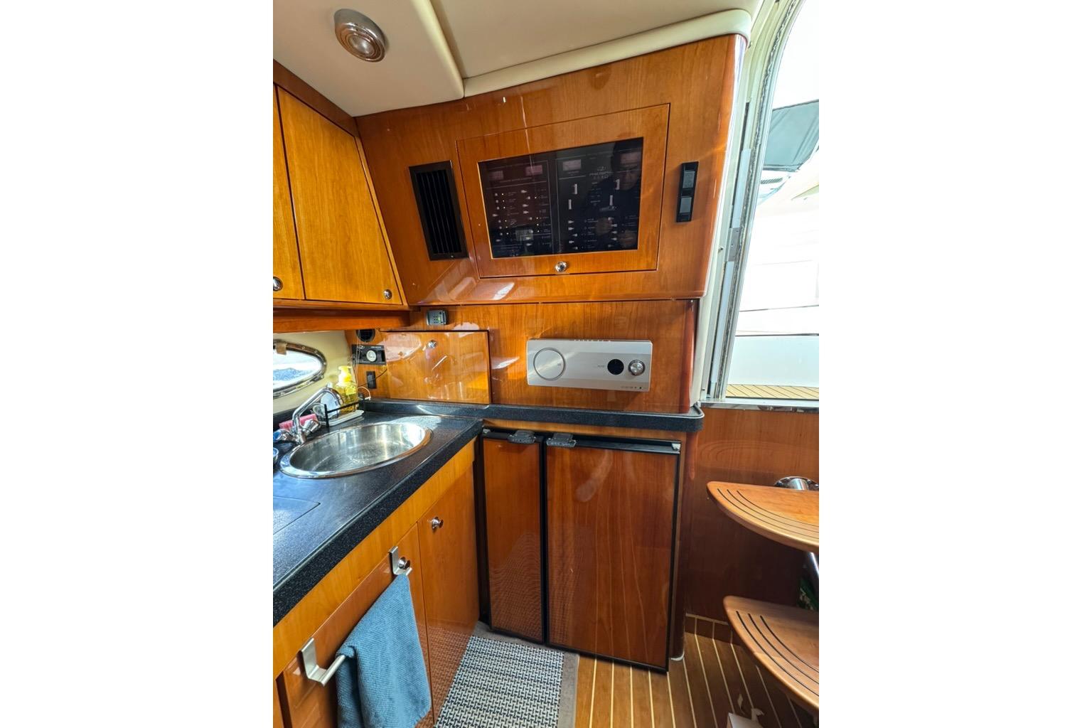 2006 Regal Commodore 4460 yacht interior with wooden cabinetry, sink, and compact appliances.