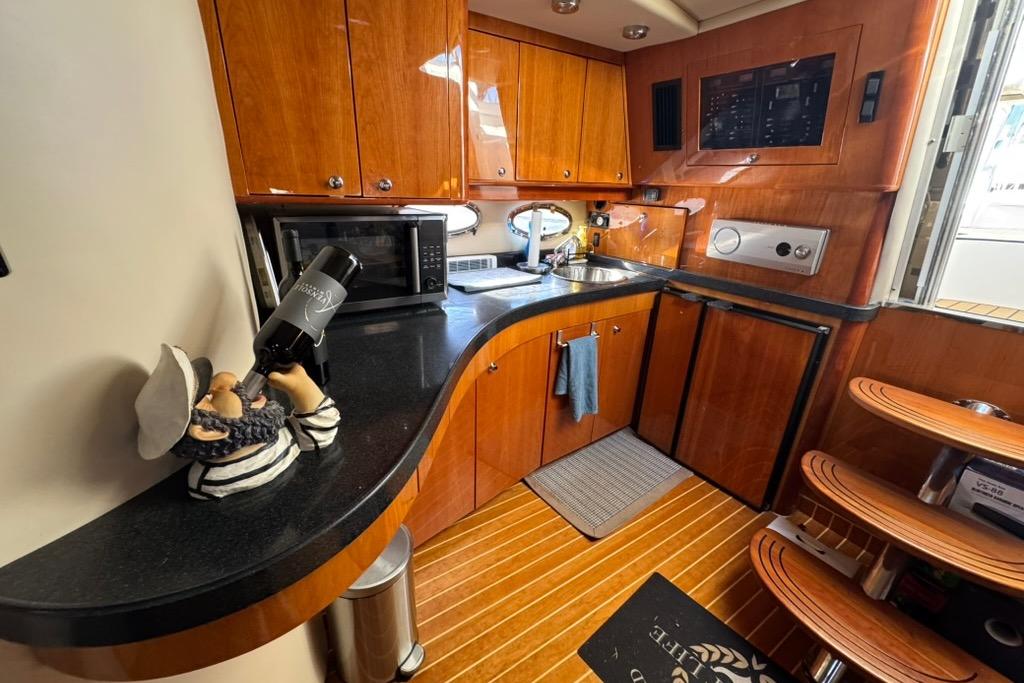 Luxurious 2006 Regal Commodore 4460 yacht kitchen with wooden cabinetry and modern appliances.