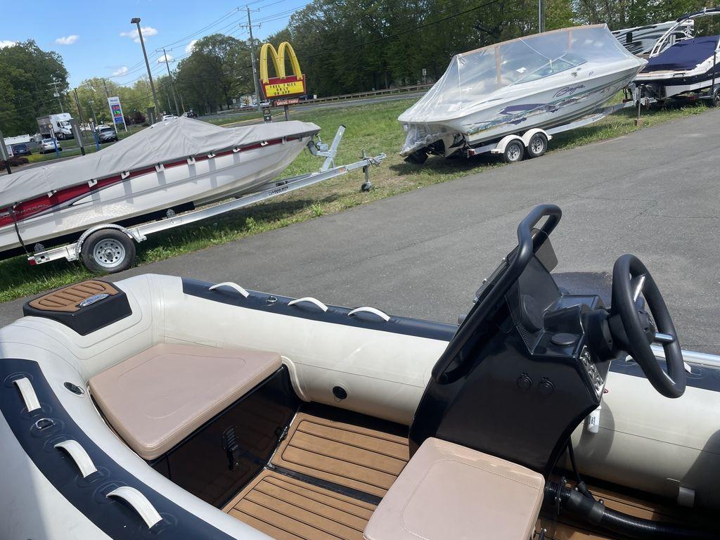 2023 Highfield Classic 380 GT Limited boat interior with steering wheel and seating, parked near trailers.