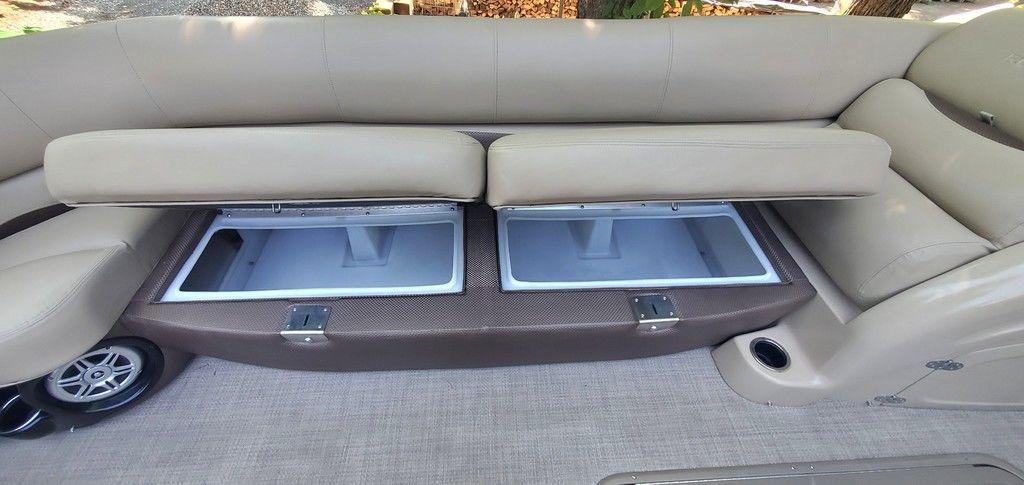 2017 Regency 220 DL3 boat interior with open storage compartments under beige seating.