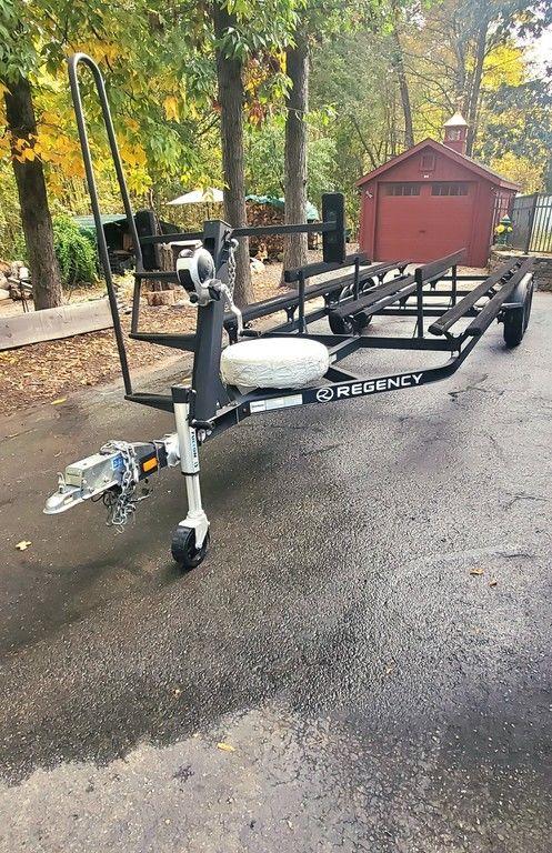 2017 Regency 220 DL3 boat trailer parked on a driveway with trees and a red shed.