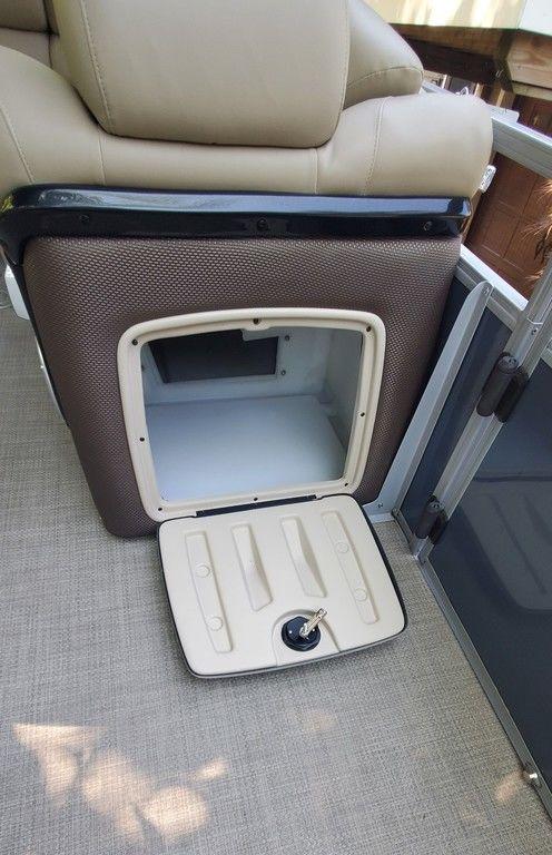 2017 Regency 220 DL3 boat storage compartment with open hatch and beige seating.