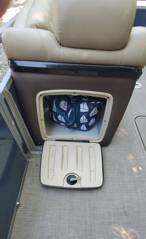 2017 Regency 220 DL3 boat storage compartment with nautical-themed bag inside.