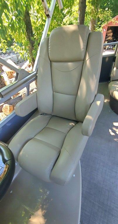 2017 Regency 220 DL3 boat seat with armrests, surrounded by lush greenery.
