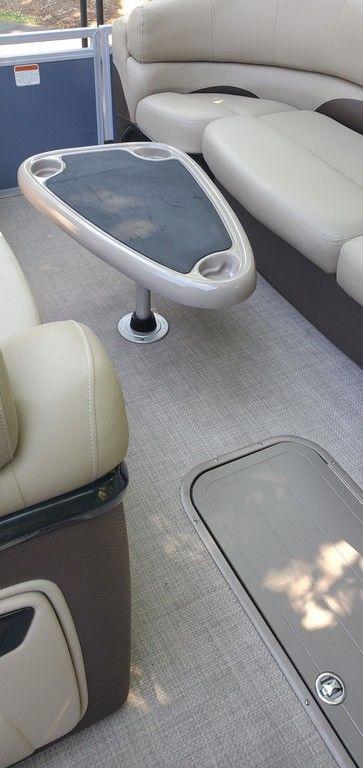 2017 Regency 220 DL3 boat interior with beige seating and a triangular table.