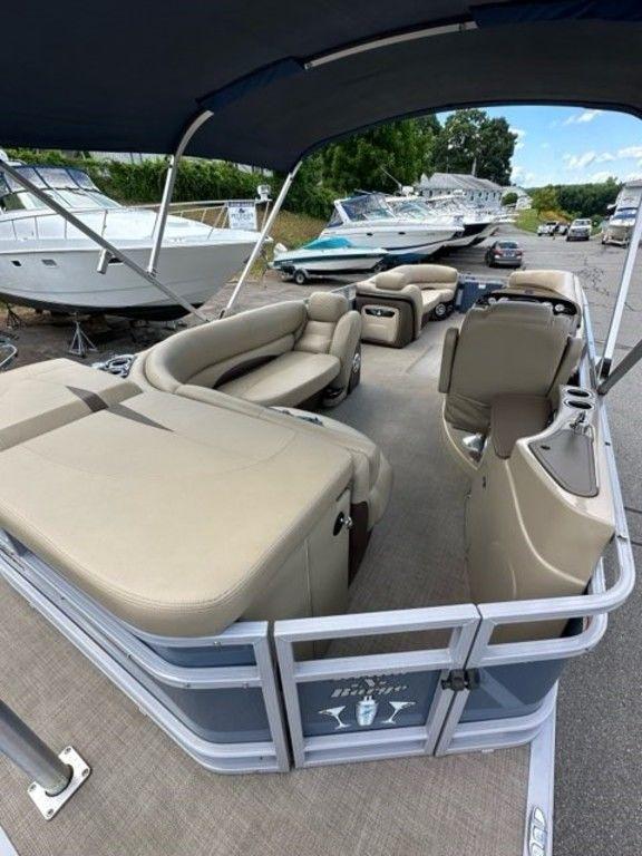2017 Regency 220 DL3 pontoon boat with beige seating and canopy, docked near other boats.