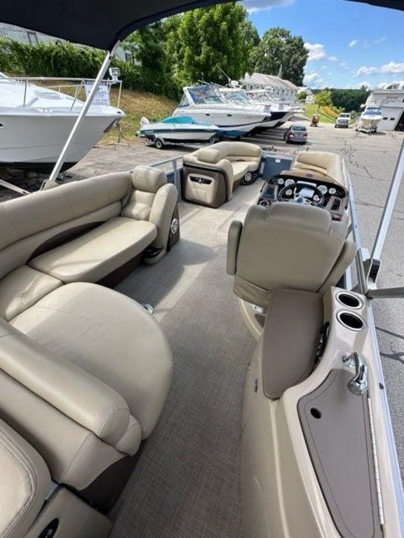 2017 Regency 220 DL3 pontoon boat with beige seating, docked near other boats.
