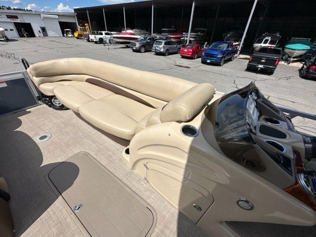 2017 Regency 220 DL3 pontoon boat with beige seating and control panel, parked in a marina.
