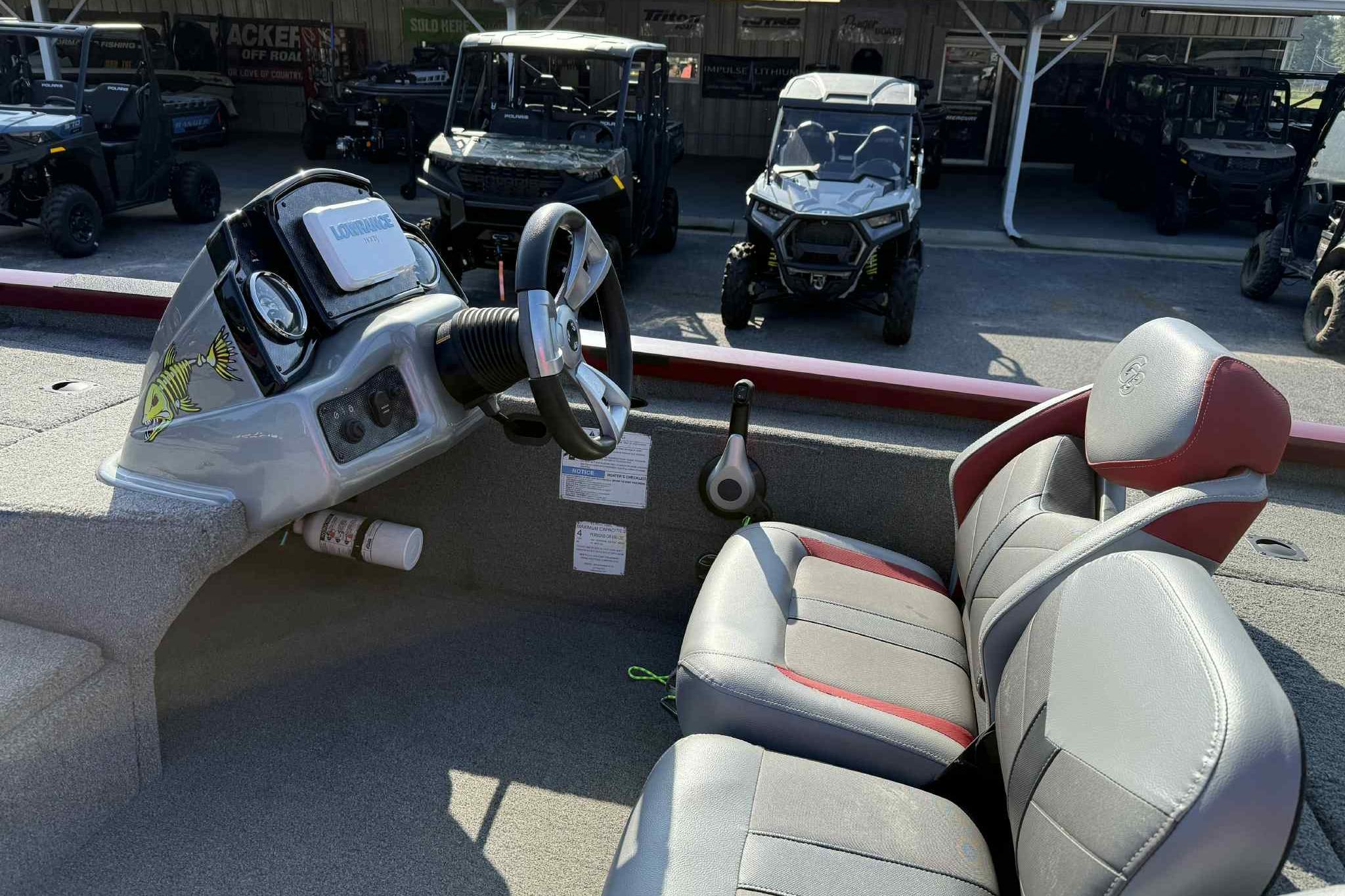 2020 G3 Sportsman 1710 boat interior with steering wheel and seats, parked near off-road vehicles.