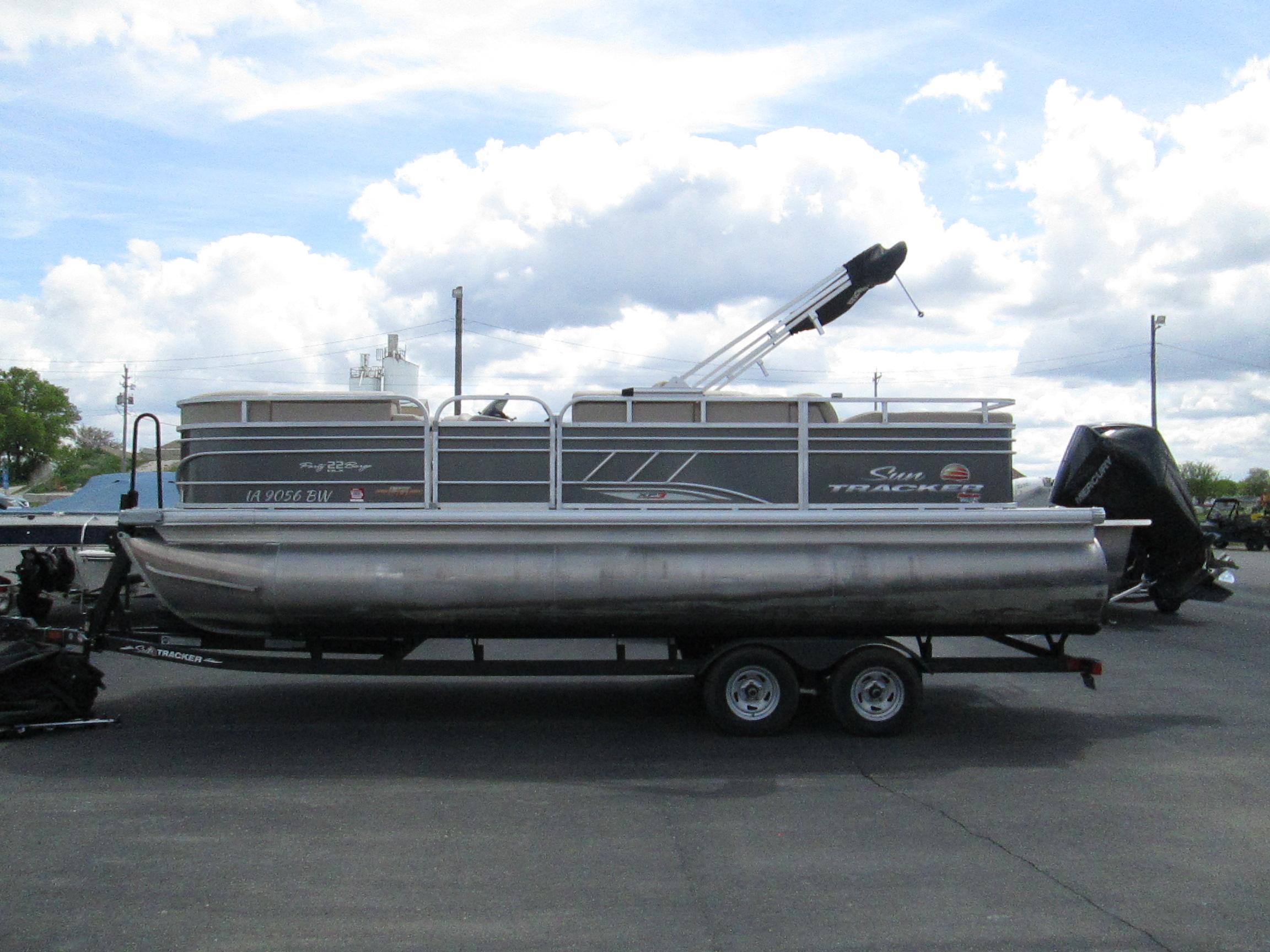 2023 Sun Tracker PARTY BARGE 22RF XP3 pontoon boat on trailer, under cloudy sky.