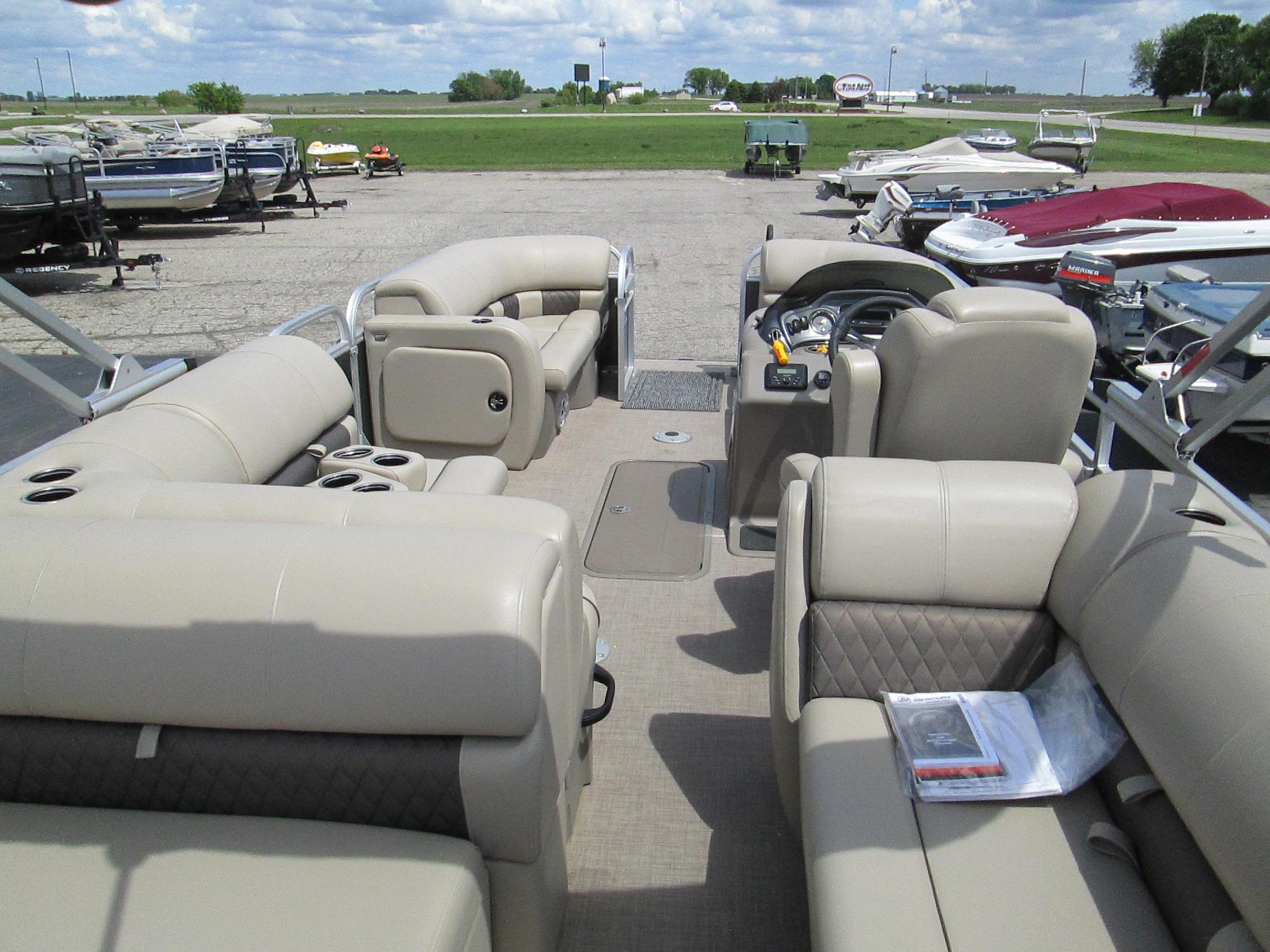 2023 Sun Tracker PARTY BARGE 22RF XP3 pontoon boat with beige seating, parked outdoors.