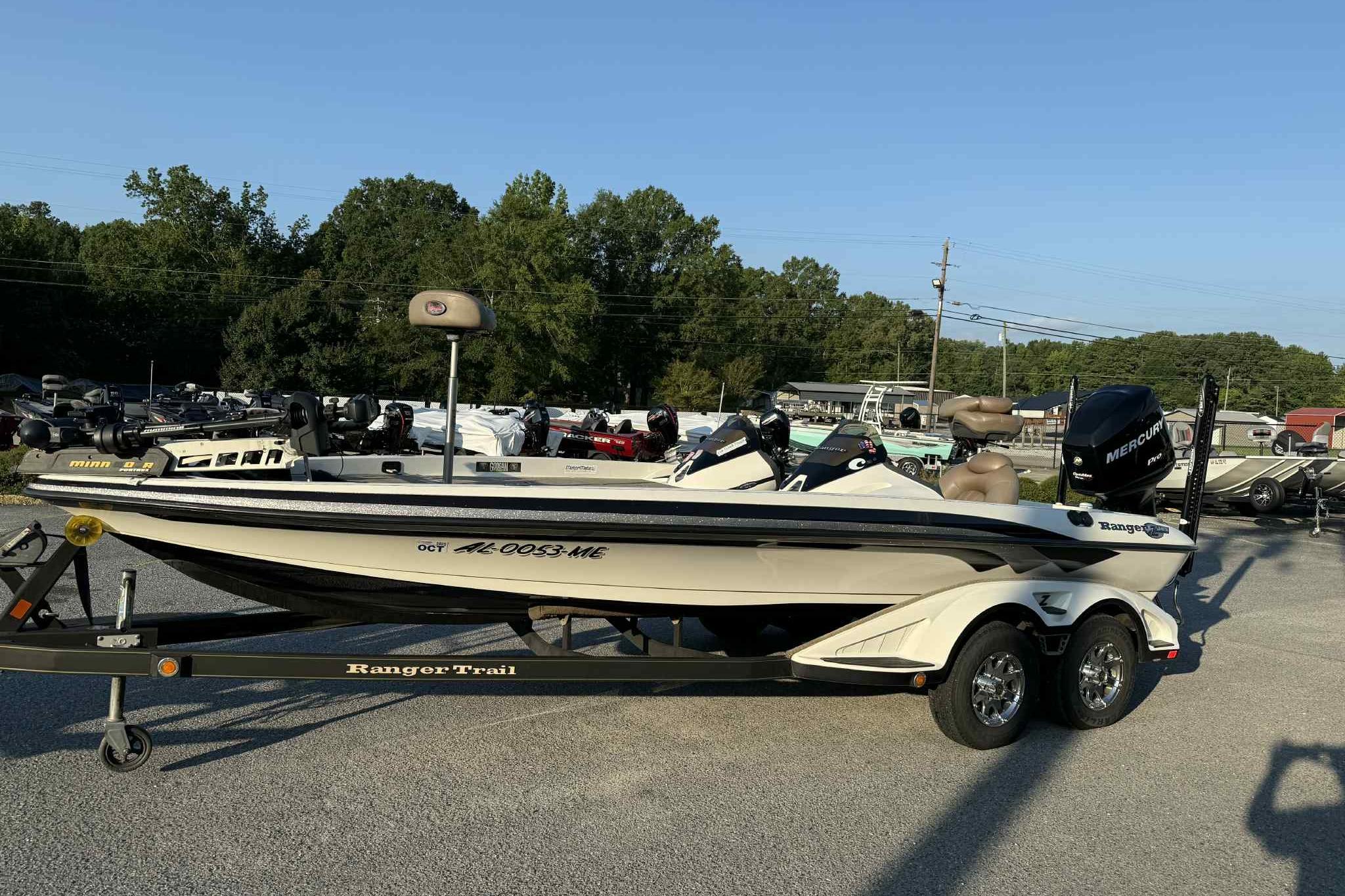 2012 Ranger Z521 Comanche boat on trailer in outdoor lot, surrounded by trees and other boats.