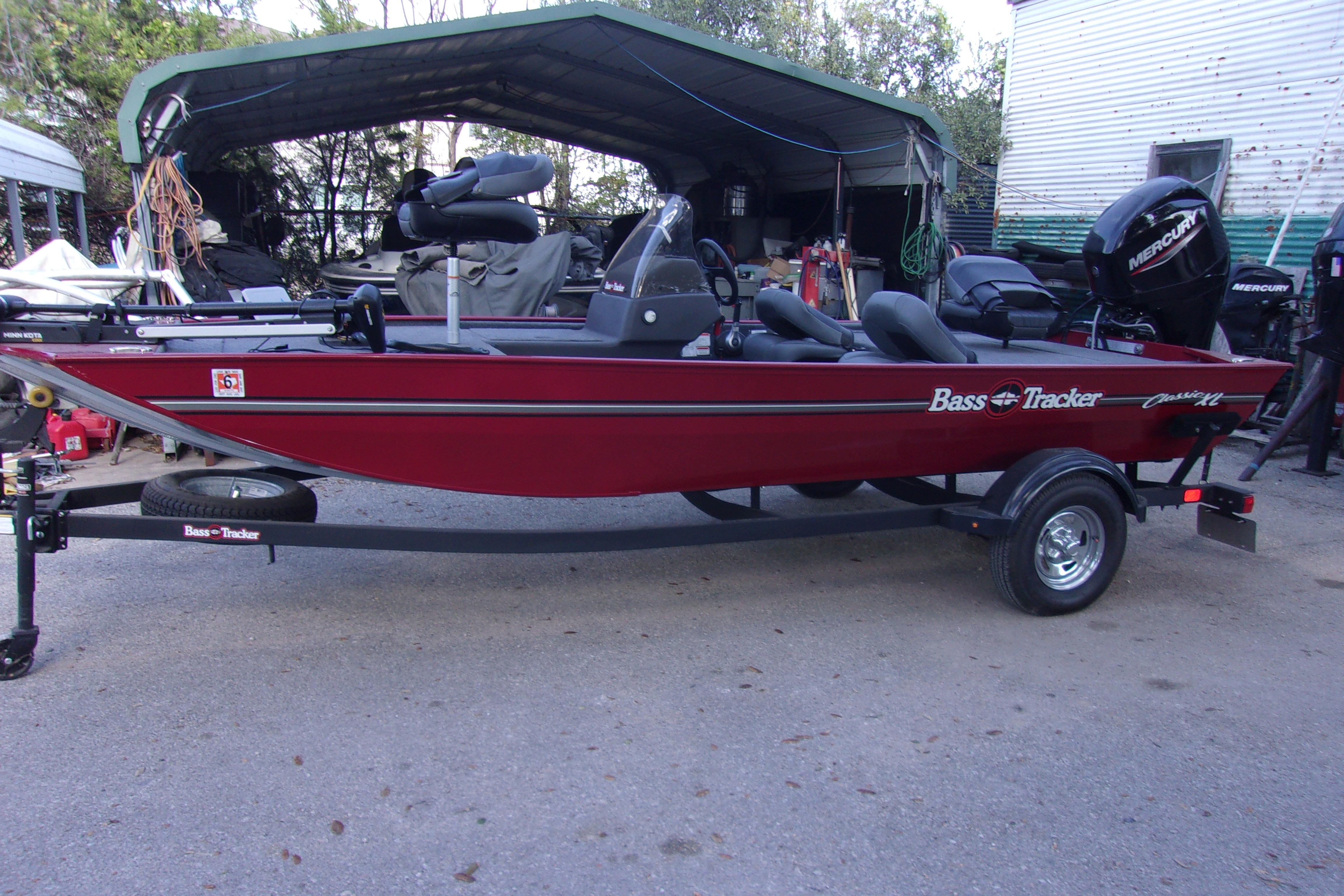 2024 Bass Tracker Classic XL boat in red, parked on a trailer outdoors.