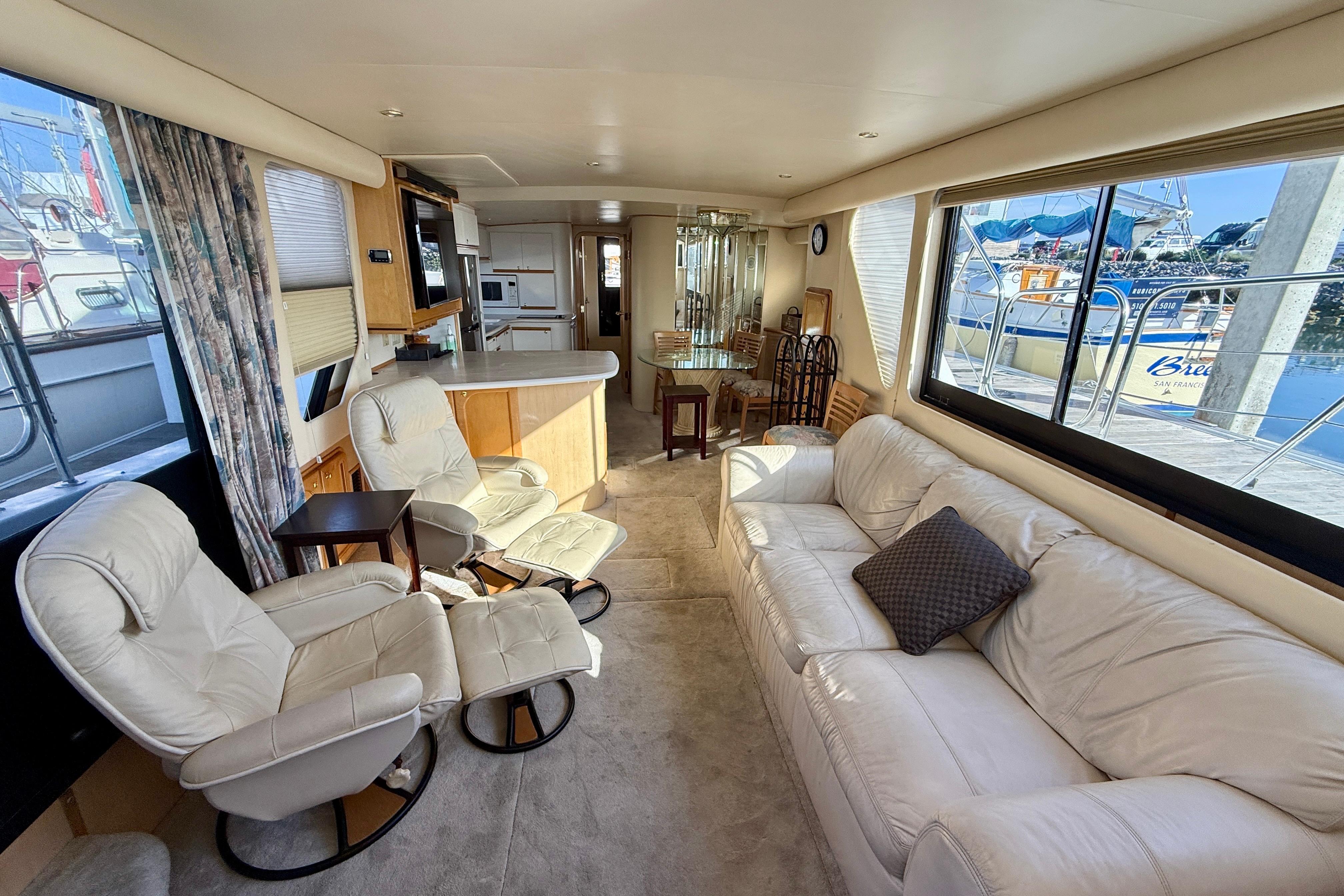 Luxurious interior of 1999 Bluewater 5800 yacht with plush seating and large windows.