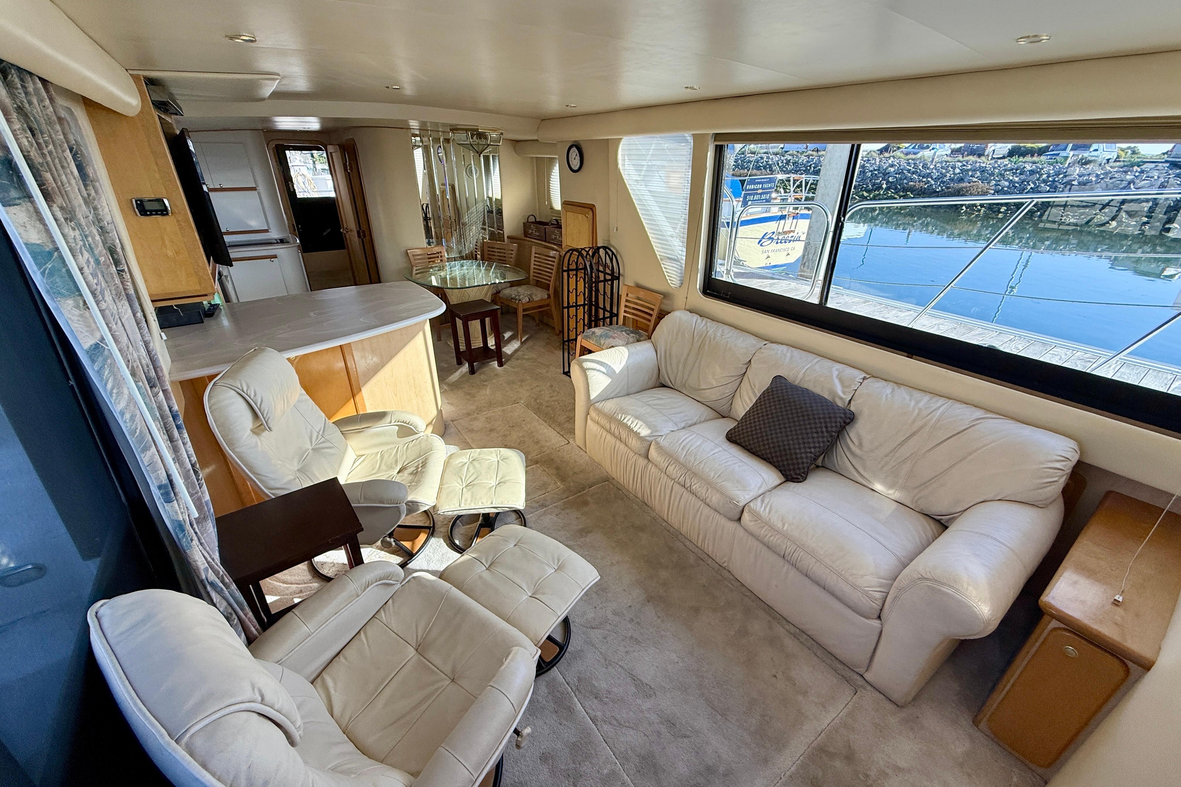 Luxurious interior of 1999 Bluewater 5800 yacht with comfortable seating and large windows.