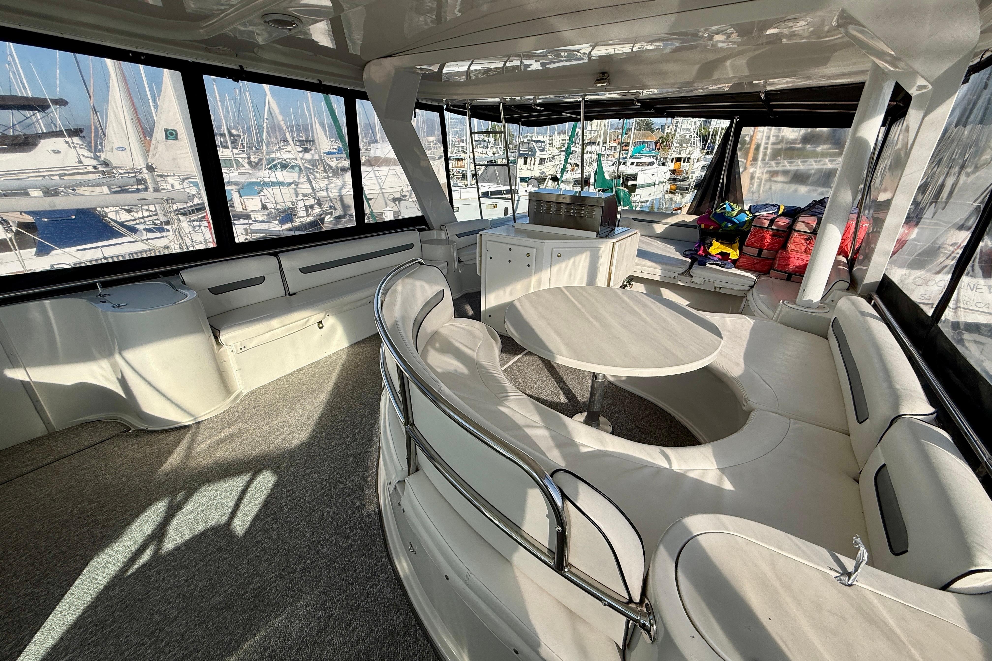 Spacious interior of a 1999 Bluewater 5800 yacht with seating and marina view.