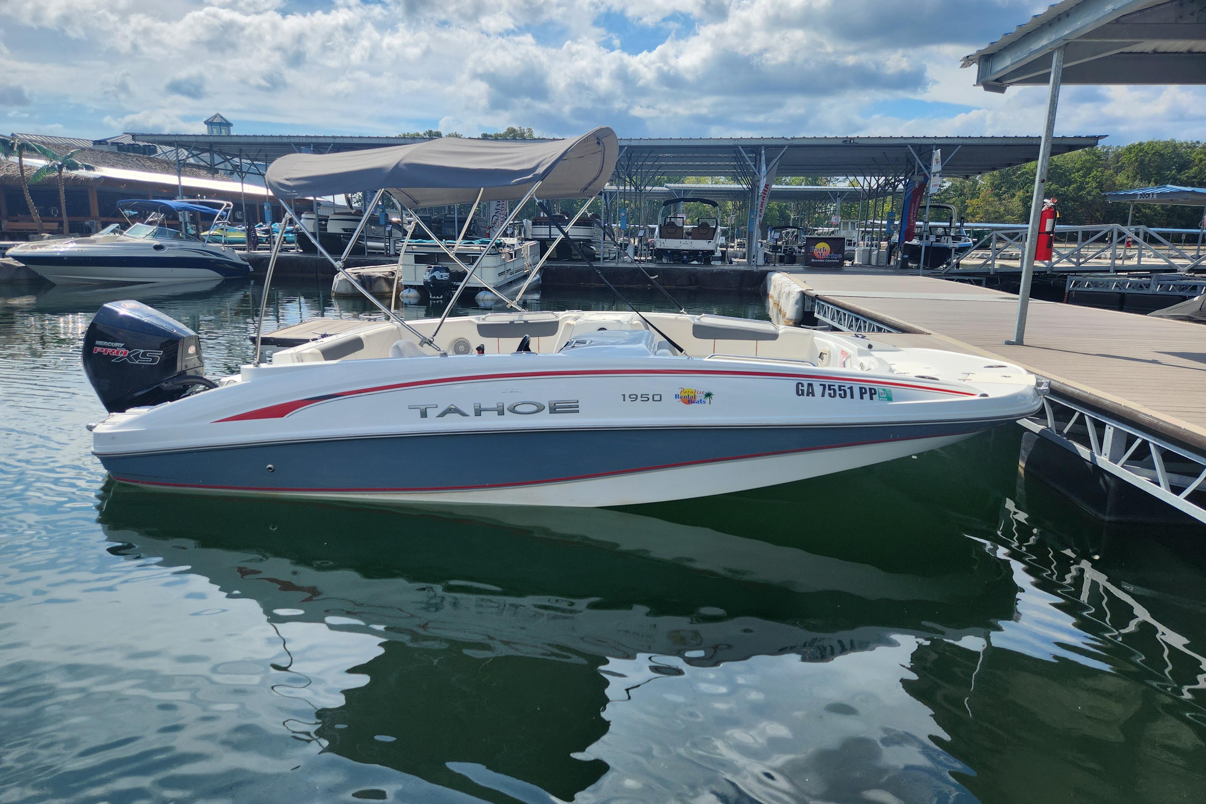 A 2021 Tahoe 1950 boat docked at a marina under a partly cloudy sky.
