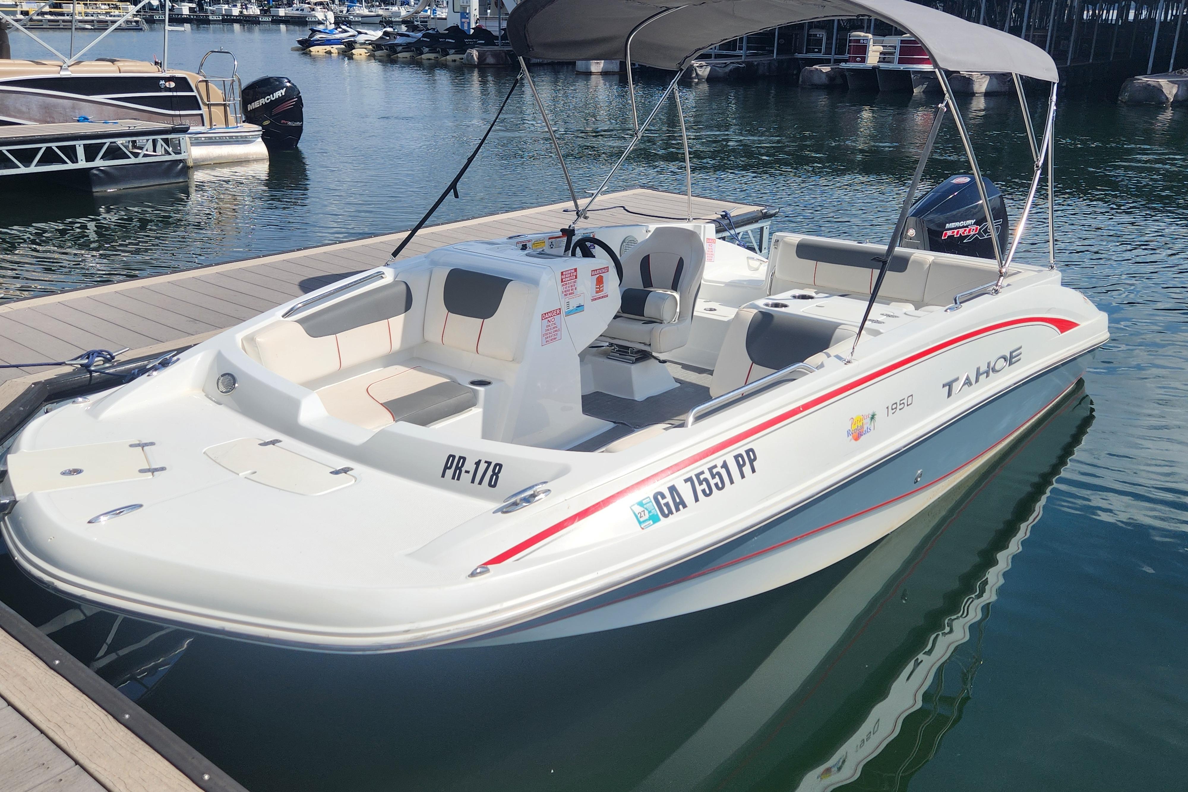 2021 Tahoe 1950 boat docked at marina, featuring spacious seating and canopy.
