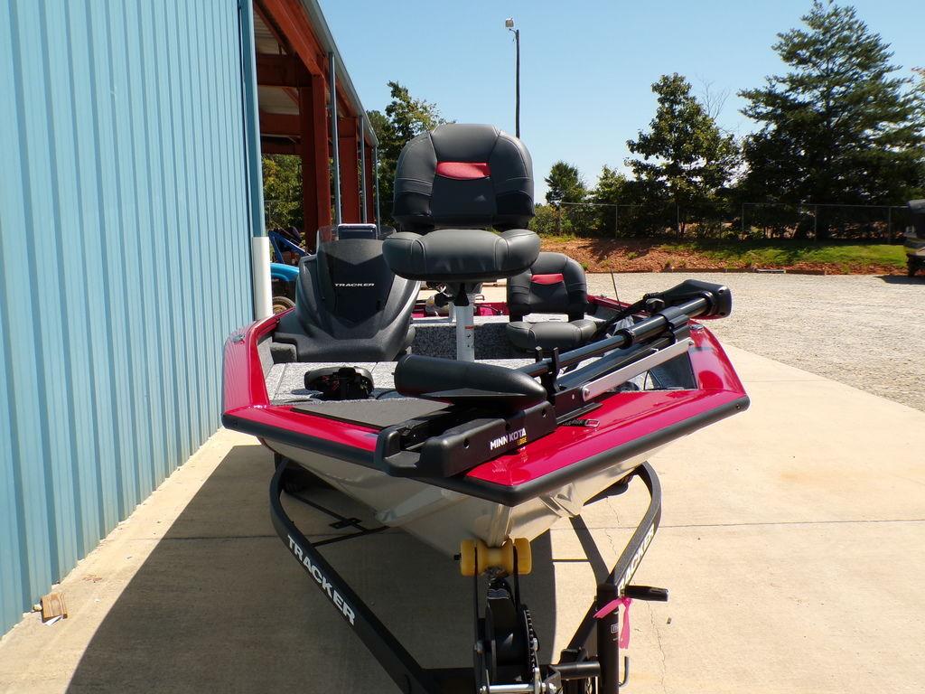 2025 Tracker Pro Team 175 TF® boat, red and gray, parked outdoors near a blue building.