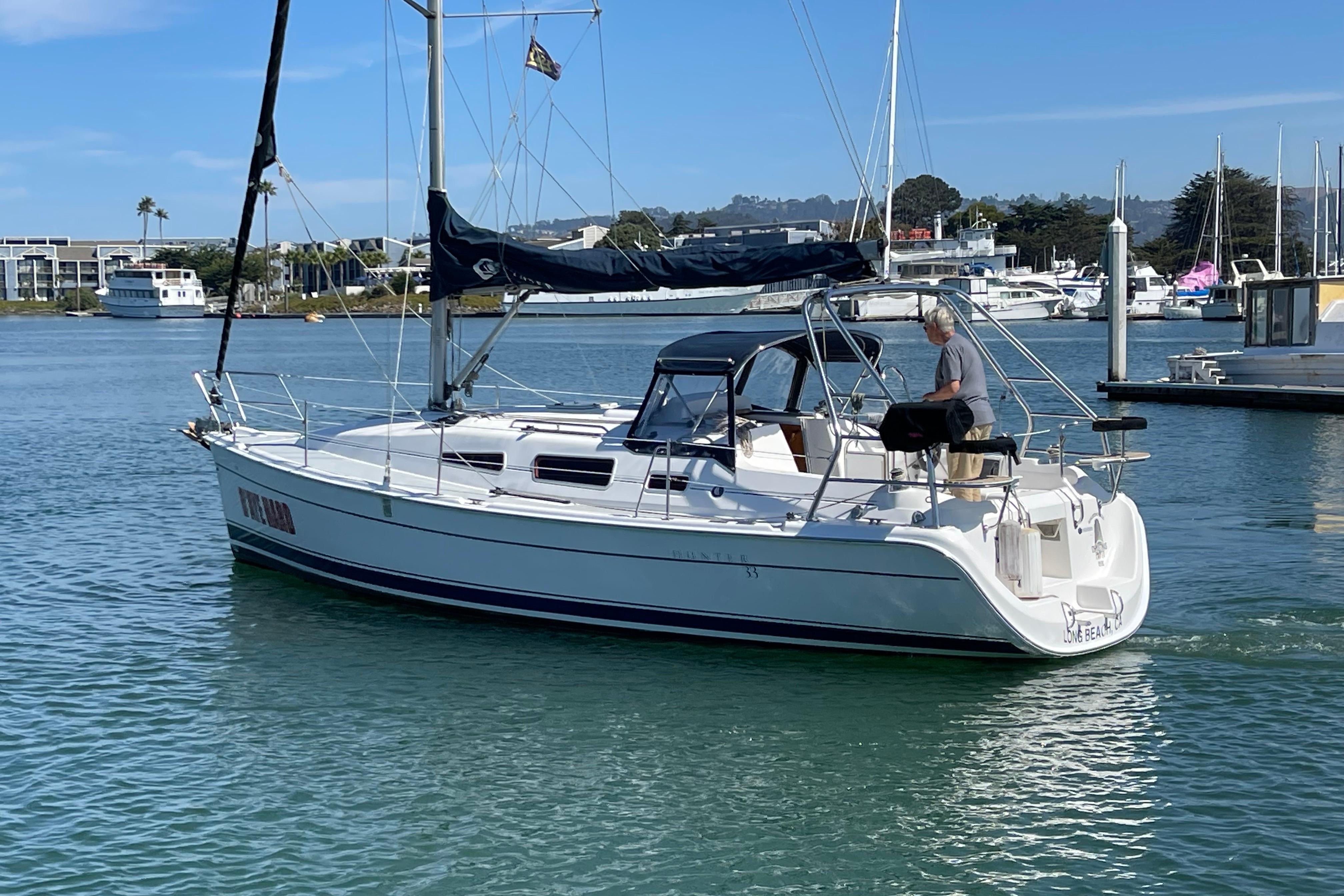 2004 Hunter 33-2 sailboat cruising in a marina with a person on deck.