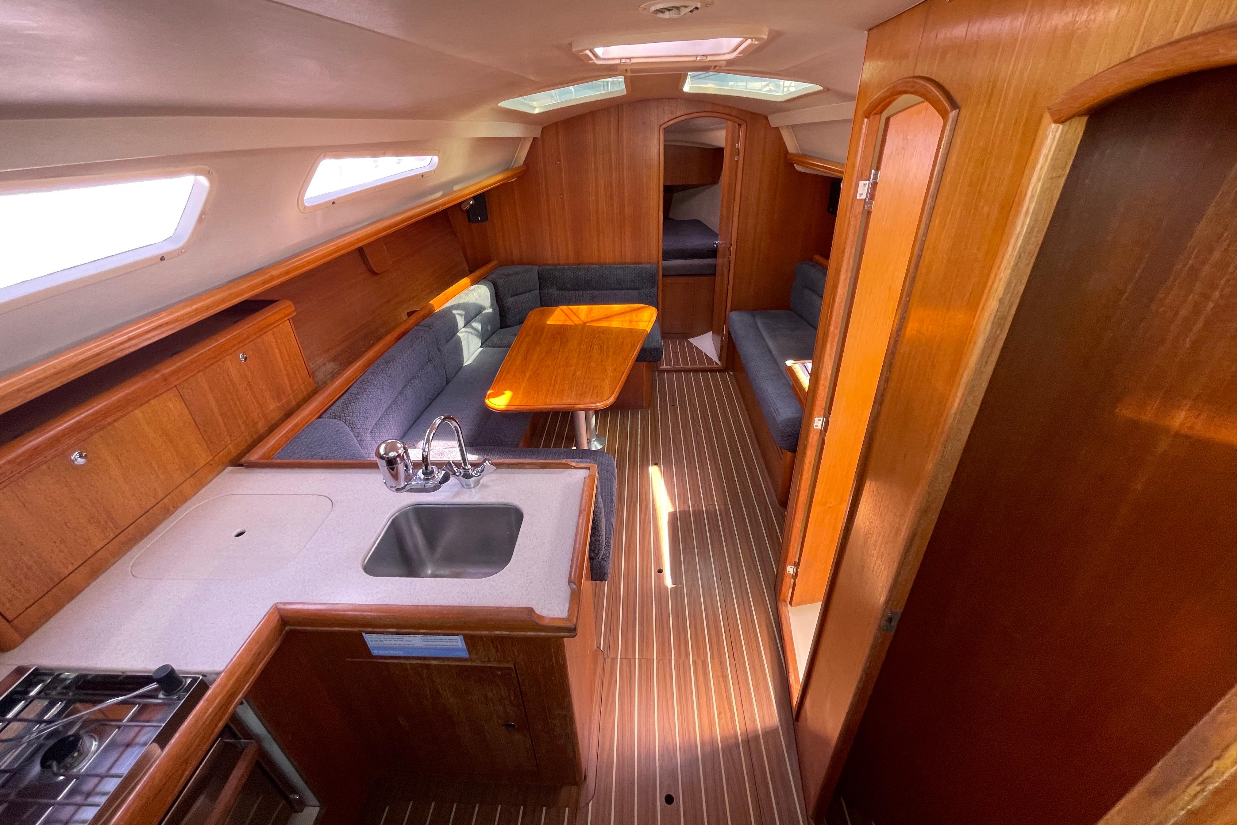 Interior of 2004 Hunter 33-2 sailboat with wood finish and compact kitchen.
