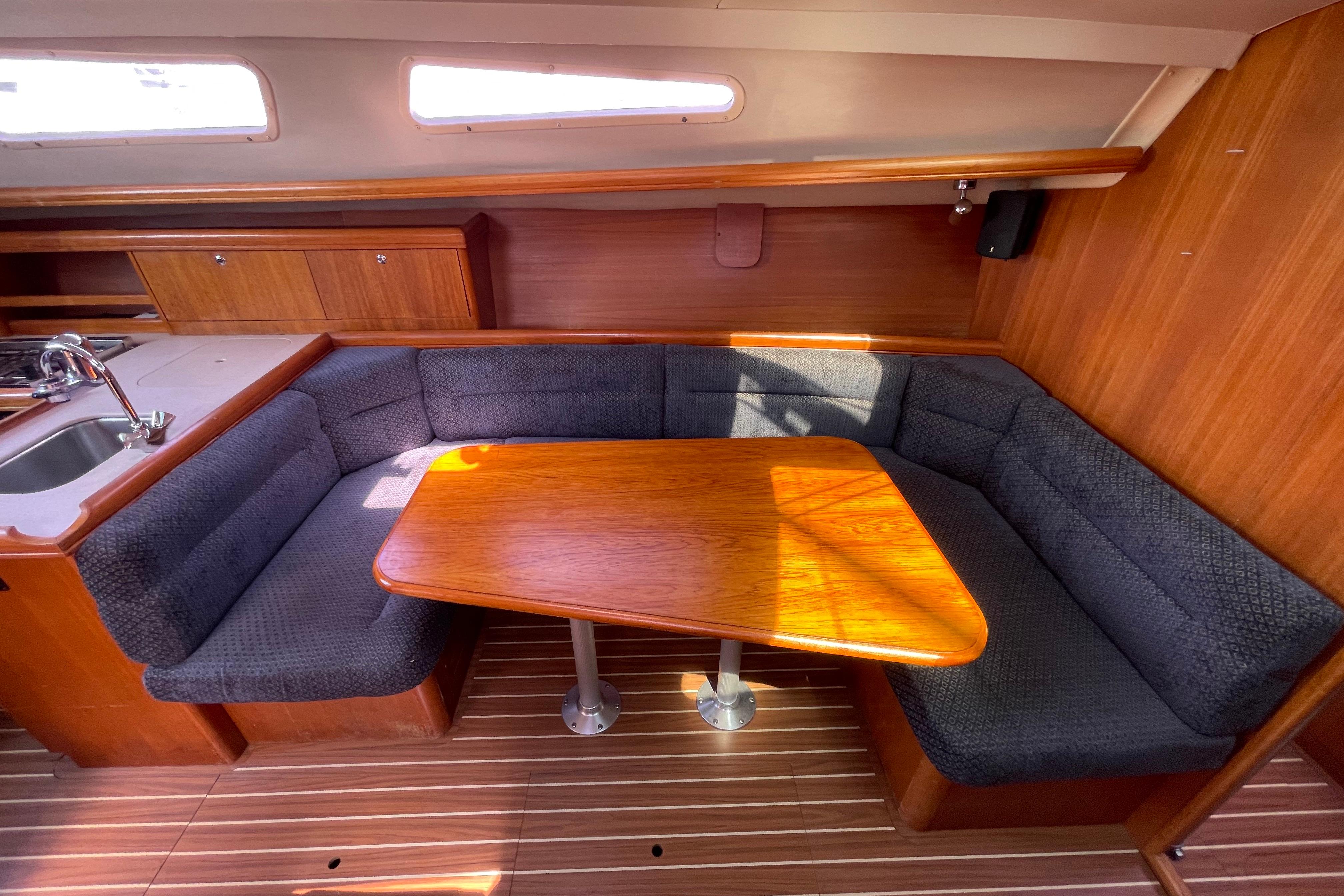 Cozy interior of 2004 Hunter 33-2 sailboat with wooden table and cushioned seating.