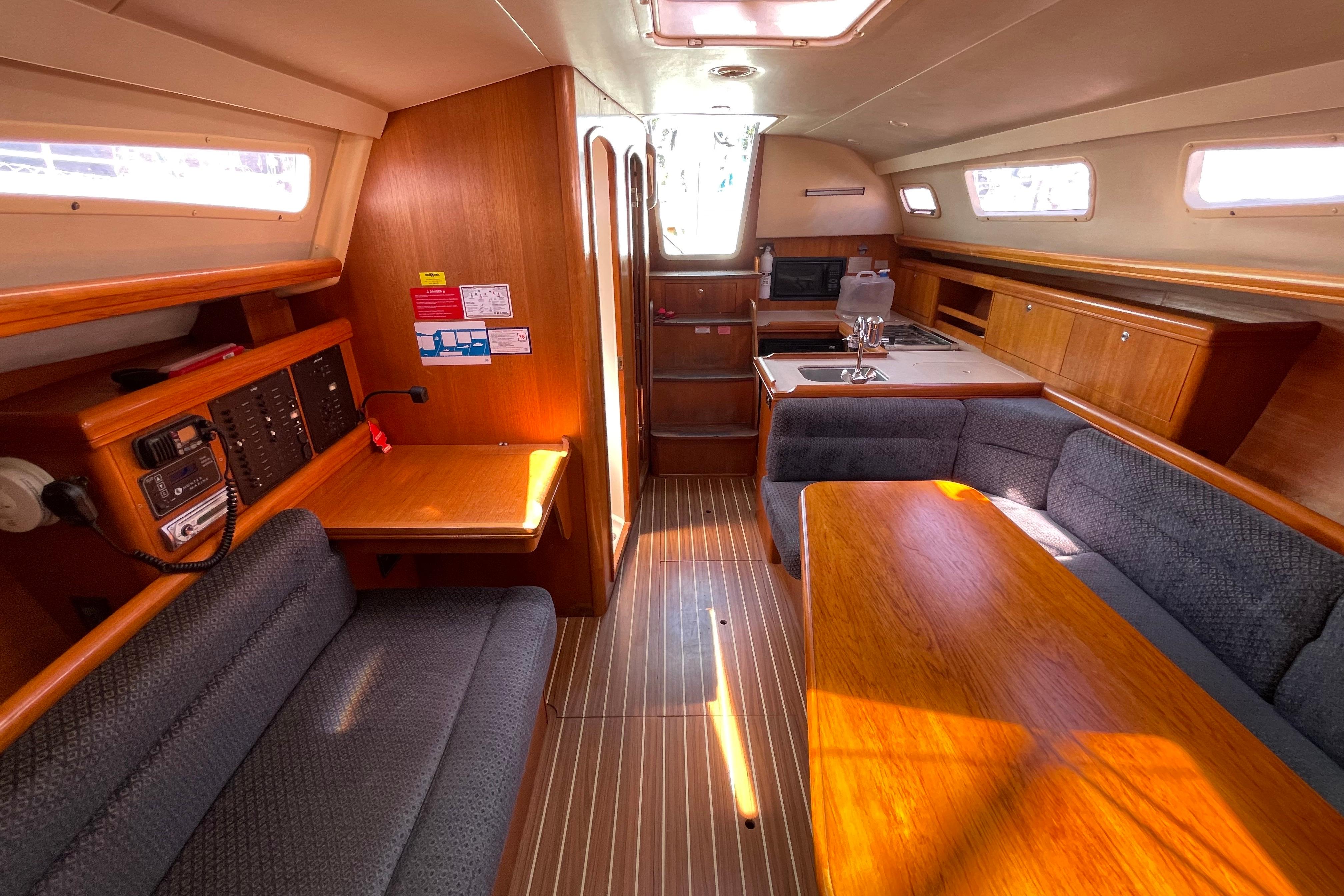 2004 Hunter 33-2 yacht interior with wood finish, seating, and kitchenette.