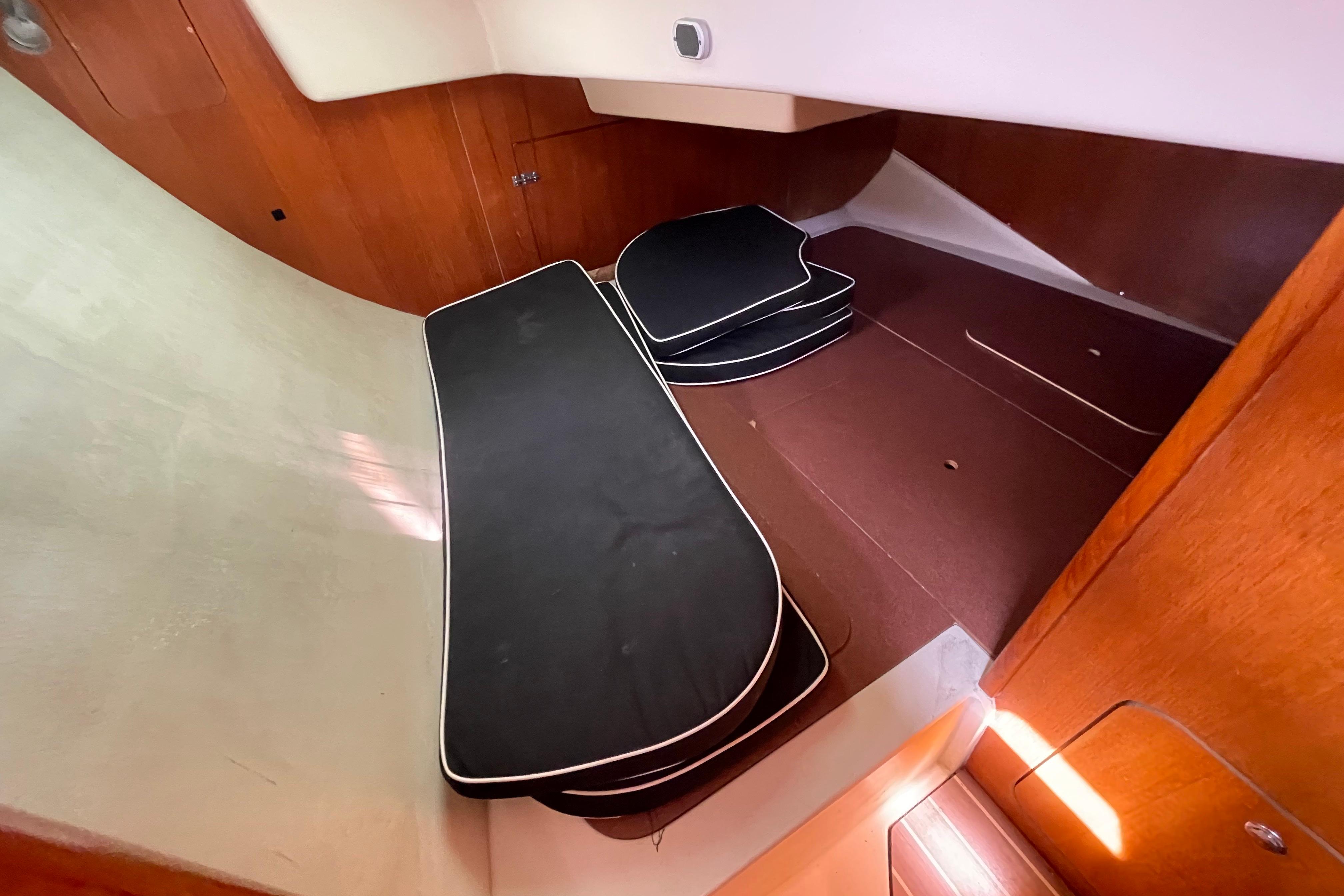 Interior cabin of a 2004 Hunter 33-2 sailboat with black cushions and wooden paneling.