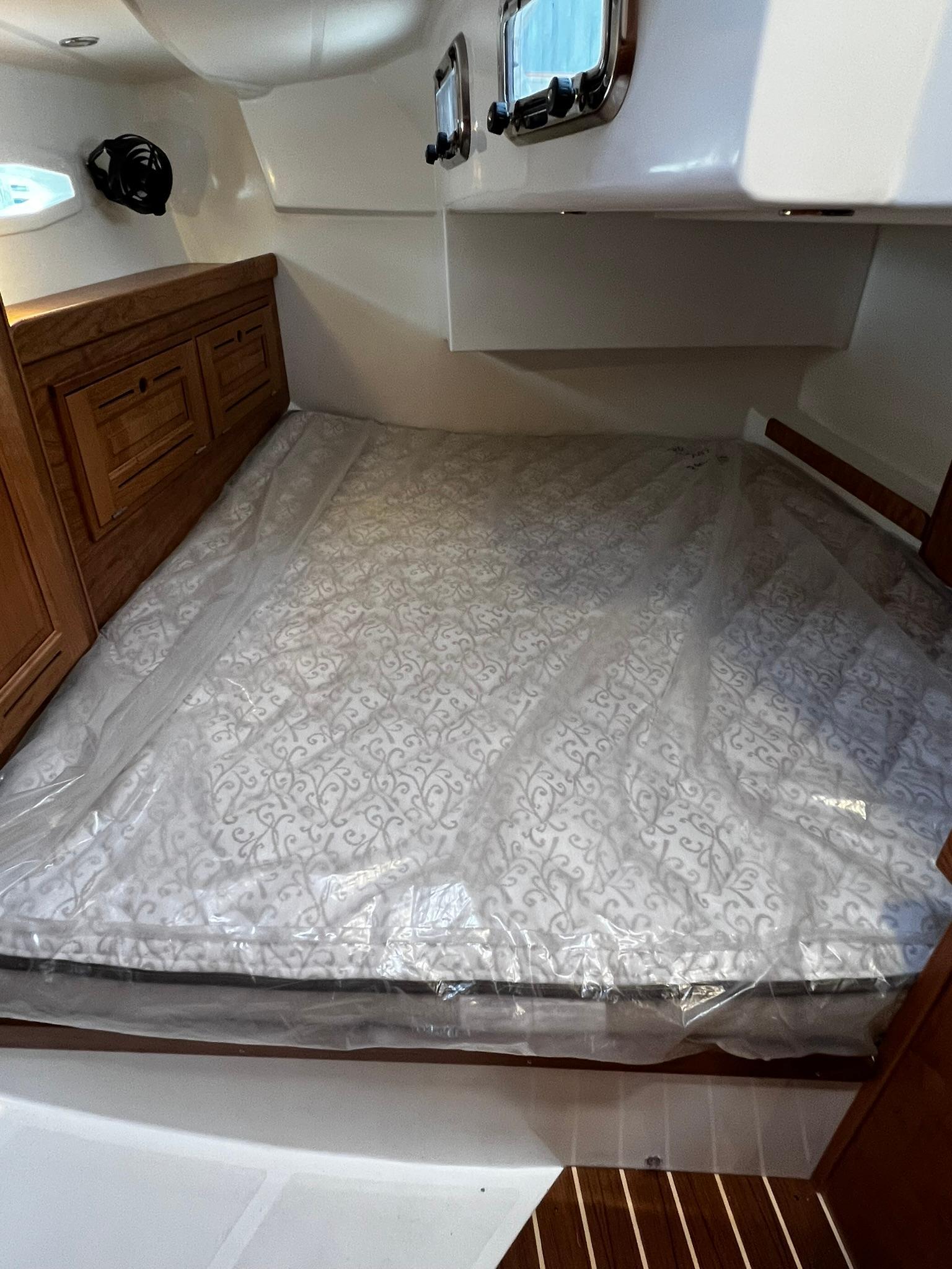 Tartan-395 2025-395 RI-US-2025 Tartan 395 cabin interior with bed, wooden cabinetry, and portholes.-9826454 | Thumbnail