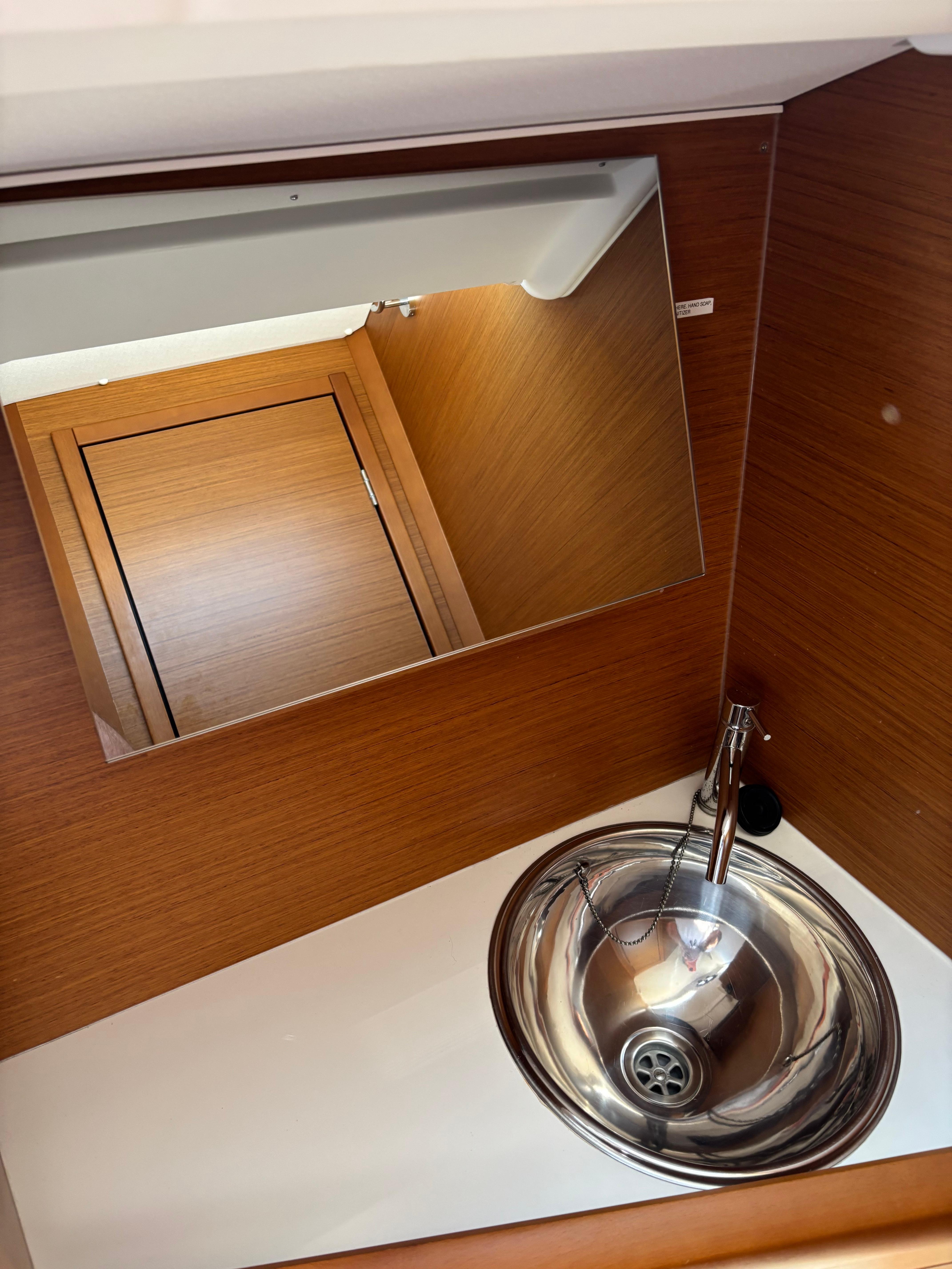 Interior of 2021 Jeanneau Sun Odyssey 349 yacht bathroom with sink and mirror.