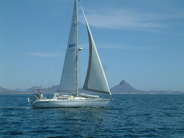 Sailboat Islander IP Peterson 40, 1979, sailing on calm sea with mountain backdrop.