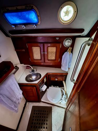 1979 Islander IP Peterson 40 yacht bathroom with sink, toilet, and wooden cabinetry.