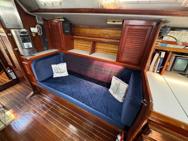 1979 Islander IP Peterson 40 yacht interior with blue cushioned seating and wooden cabinetry.